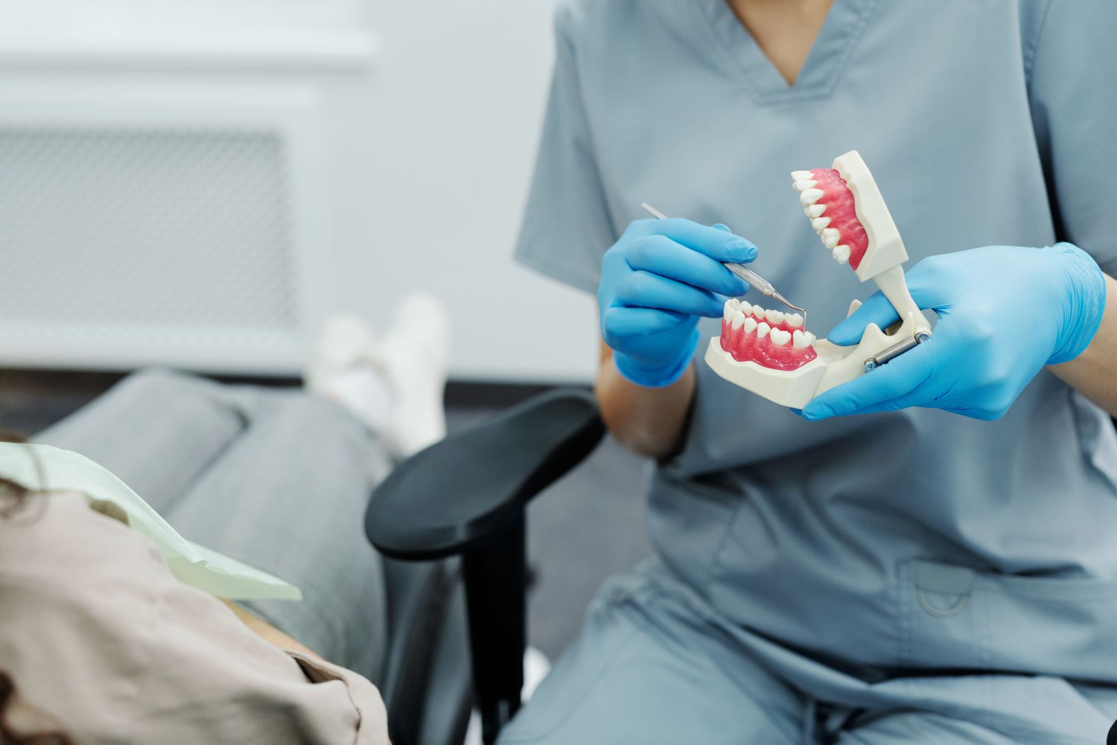 A dental professional demonstrating treatment using a physical teeth model